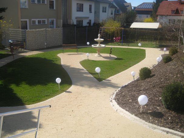 Garten Garten mit Rasen, Pflanzen mit Springbrunnen und einer weißen Kugelbeleuchtung entlang der Wege.