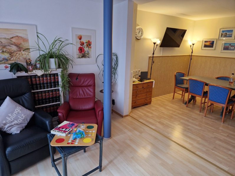 Wohnzimmer mit Sessel, Tisch und Esstisch in einer hellen, einladenden Umgebung.